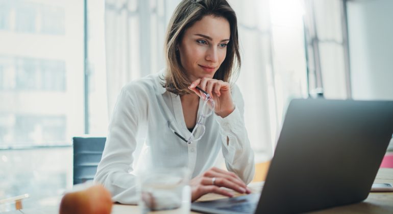 Confident businesswoman working on laptop at her workplace at modern office.Blurred background.